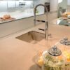 Encimera Neolith Arena en cocina con fregadero, grifo y tarros de comida, tono beige cálido