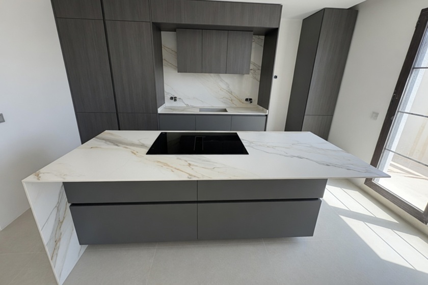 Isla de cocina con encimera de porcelánico fino de 1.2 cm con veta dorada en proyecto moderno