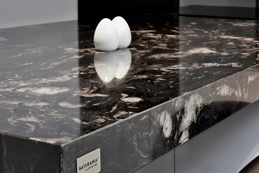 Encimera de granito Titanium Gold con fondo negro exótico y vetas doradas, vista cercana con accesorios minimalistas, resistente y lujosa para reformas premium en la ciudad de Málaga.