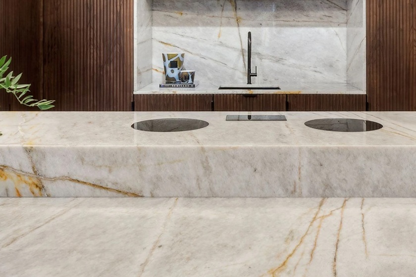 Encimera de cuarcita Naturamia Nuur para cocina moderna de Málaga, con fondo blanco crema y vetas doradas, resistente y elegante para reformas premium