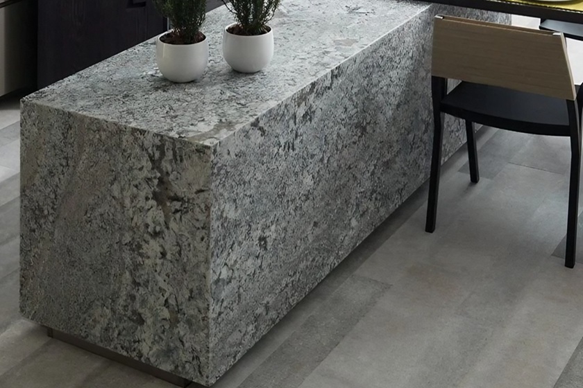 Encimera de granito blanco Naturamia Lennon en cocina minimalista de Málaga, con textura grisácea y plantas decorativas, resistente y elegante para reformas premium.