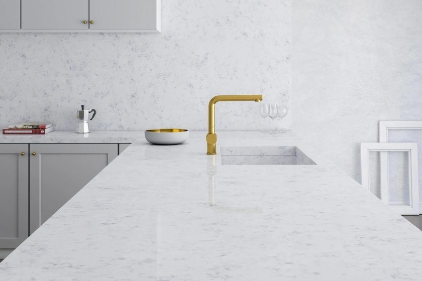 Texto alternativo (alt text) optimizado para SEO y accesibilidad (en español):
Encimera Topzstone Venatino en cocina blanca moderna con grifo dorado, fregadero integrado y detalles minimalistas vista superior de isla