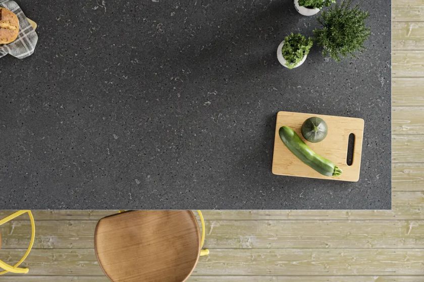 Encimera de cuarzo Silestone Cinder Craze en isla de cocina moderna con tabla de cortar y verduras frescas vista superior