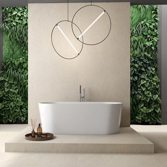 Baño spa con bañera blanca, grifo, luces circulares y pared verde vegetal sobre suelo Arklam Bateig Verona beige.