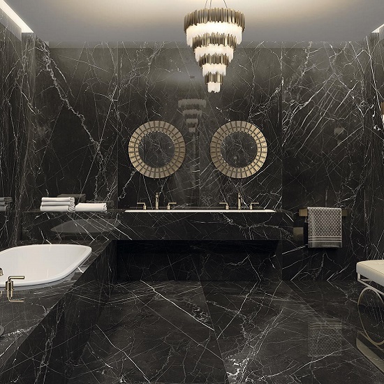 Baño de lujo con revestimientos y encimeras Arklam Negro Marquina en Málaga, bañera blanca y grifería dorada.