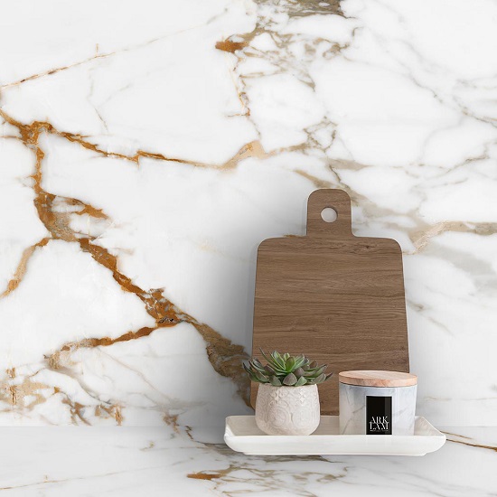 Encimera Arklam Calacatta Gold con tabla de cortar, planta y vela, superficie resistente a manchas para cocinas en Málaga