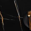 Encimera Arklam Sahara Noir negra con vetas doradas, decorada con plato y cubiertos para cocinas en Málaga.
