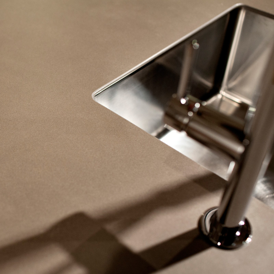 Primer plano de fregadero en encimera Neolith Barro terracota con grifo y sombra detallada.