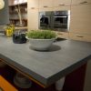 Isla de cocina Neolith Basalt Grey Málaga, diseño gris con plantas y vitrocerámica.