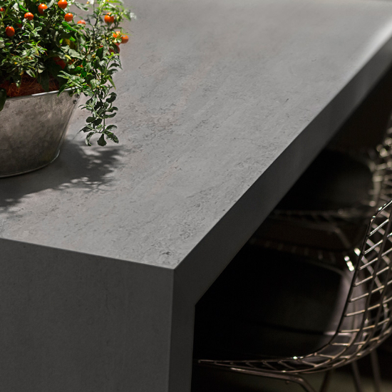 Superficie Neolith Beton Málaga con planta decorativa, textura gris resistente en cocina.