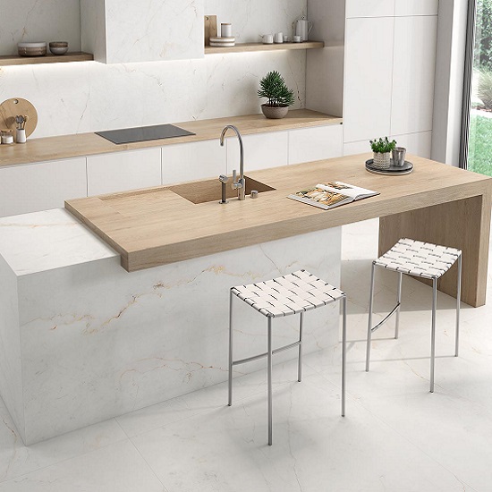 Isla de cocina Arklam Arcane Camel madera con taburetes blancos, gabinetes negros y pared gris.