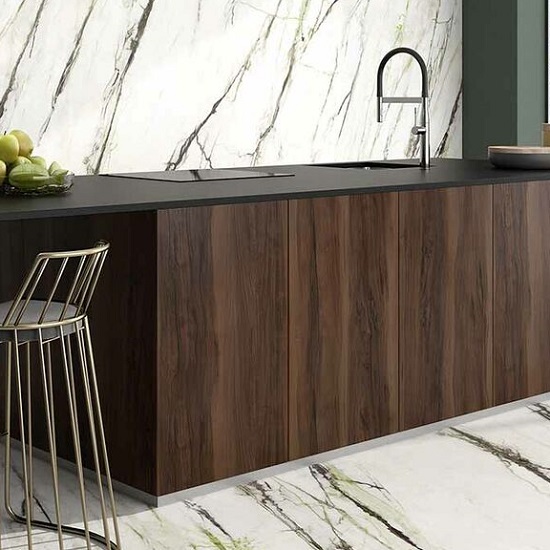 Encimera Arklam Canada madera con bol de peras, fregadero y gabinetes negros en cocina moderna.
