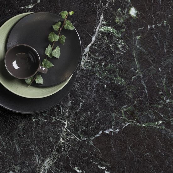 Encimera Arklam Caviar Green en verde oscuro con vetas naturales, ideal para cocinas en Málaga, decorada con platos y planta.