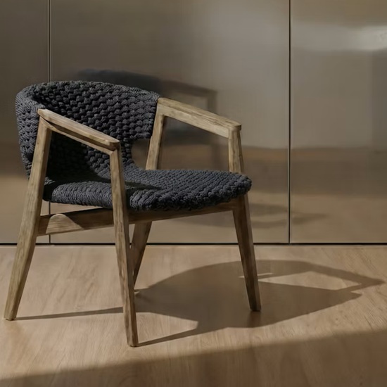 Silla tejida oscura con brazos de madera sobre suelo Dekton Kedar en tono roble cálido, en entorno minimalista.