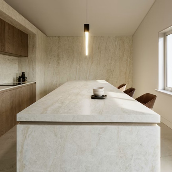 Isla de cocina en Dekton Nara con taburetes madera, grifo dorado y gabinetes oscuros.