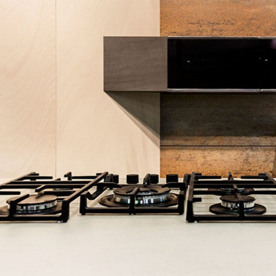 Fogones de gas negros sobre encimera blanca Neolith Arctic White en cocina moderna.