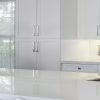 Encimera blanca Neolith Arctic White en cocina con gabinetes blancos y ventana luminosa.