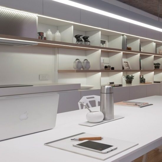 Superficie blanca Neolith Arctic White con laptop, termo y accesorios en entorno de oficina.