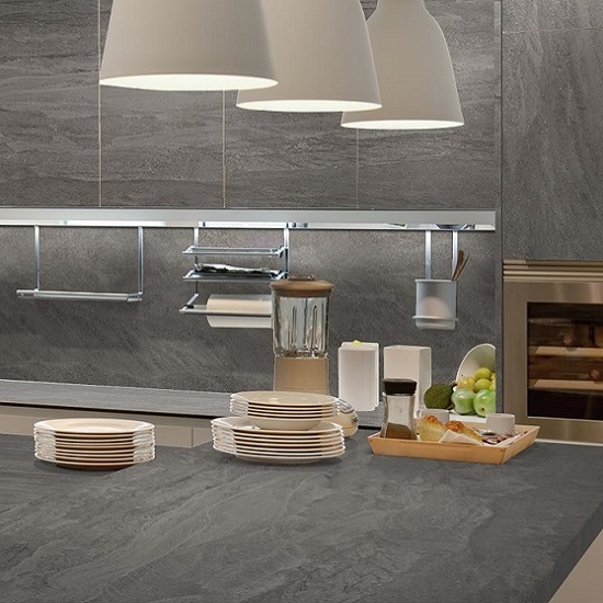 Encimera Neolith Aspen Grey gris con platos, licuadora y accesorios en cocina moderna con lámparas.