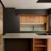 Isla de cocina Neolith Beton Málaga, diseño gris minimalista con taburetes y madera.