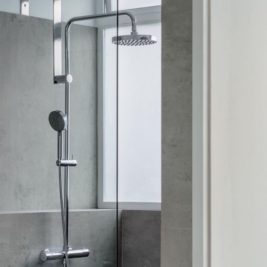 Ducha con revestimiento Neolith Beton Málaga, diseño gris industrial con grifo moderno.