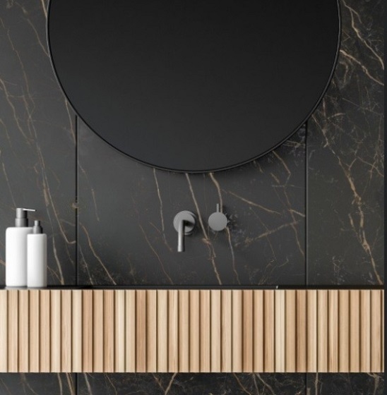 Detalle de lavabo Neolith Black Obsession Málaga, superficie negra dorada con espejo y dispensadores.
