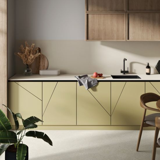 Cocina moderna con encimera Neolith Creme, gabinetes amarillos geométricos y fregadero negro, ideal para hogares en Málaga