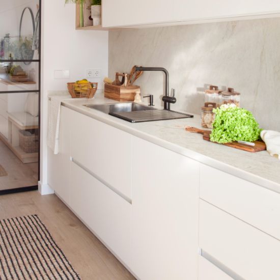 Encimera Neolith Taj Mahal en cocina blanca Málaga, con fregadero y accesorios naturales.