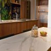 ncimera Blaker Toscana Gold blanca veteada con jarra, frutas y gabinetes de madera en cocina moderna.