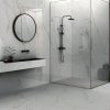 Baño moderno con ducha de vidrio, espejo redondo, lavabo negro y revestimientos Blaker Calacatta Oro blancos con vetas doradas.