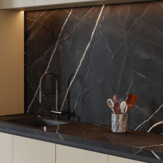 Cocina moderna con encimera y salpicadero Venux Calacatta Black negra veteada, grifo plateado y utensilios en ambiente elegante.
