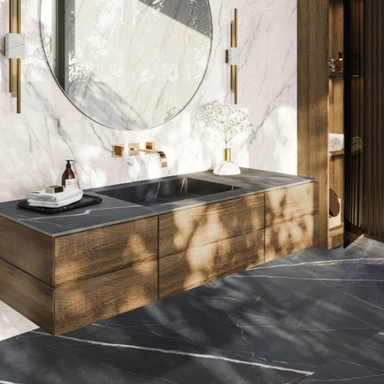 Baño moderno con encimera de baño Venux Calacatta Black negra veteada, espejo redondo, grifo dorado y toalla en ambiente cálido