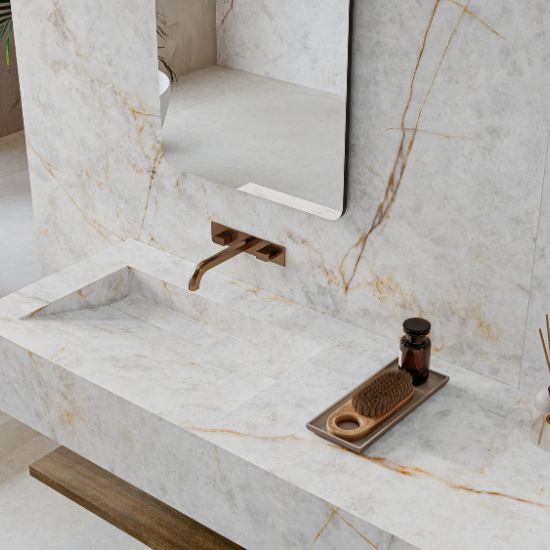 Vanitorio flotante Venux Aurora Crystal blanca veteada con espejo redondo, grifo bronce y productos en baño elegante.