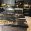 sla de cocina completa en Granito Black Taurus con muebles oscuros y encimera negra con vetas doradas
