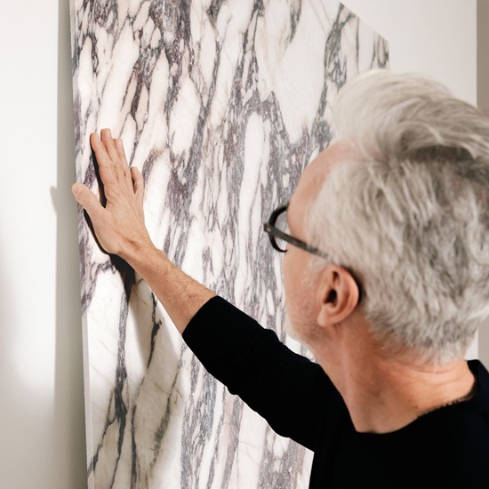 Hombre tocando una losa de Sapienstone Fior di Viola 4D, destacando la veta pasante y la textura del mármol efecto