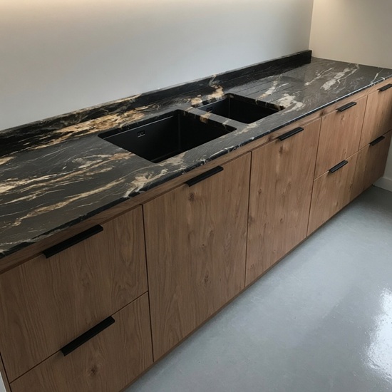 Encimera de cocina con doble fregadero negro en Cuarcita Belvedere y muebles de madera clara