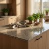 Detalle de encimera en Granito Crema Camelia con plantas aromáticas y reflejos de luz natural