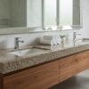 Mueble de baño flotante doble en Granito Crema Camelia con dos fregaderos, grifería cromada y toallas blancas