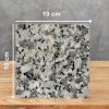 Muestra 10 x 10 cm de Granito Crema Julia con motas negras y grises sobre madera