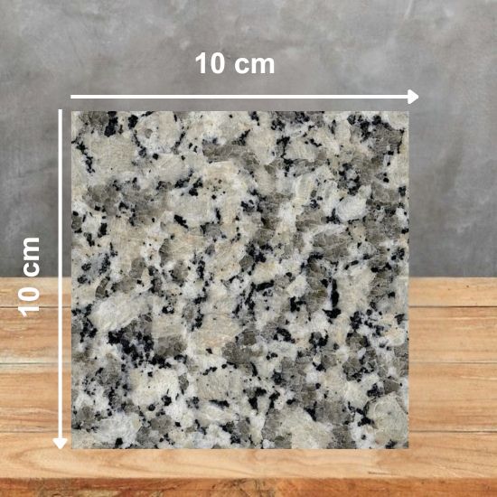 Muestra 10 x 10 cm de Granito Crema Julia con motas negras y grises sobre madera