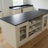 Isla central de cocina en Pizarra Negra Lisa con muebles crema y estantería abierta