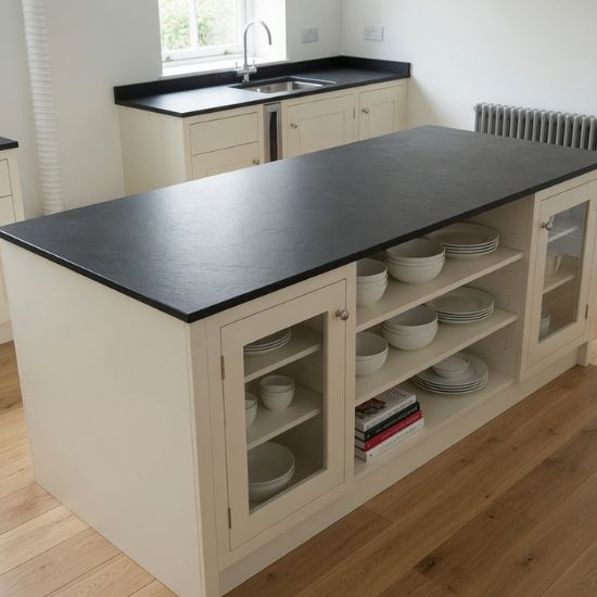 Isla central de cocina en Pizarra Negra Lisa con muebles crema y estantería abierta