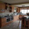 Cocina completa con encimeras de Granito Steel Gray, muebles de madera clara e isla con taburetes