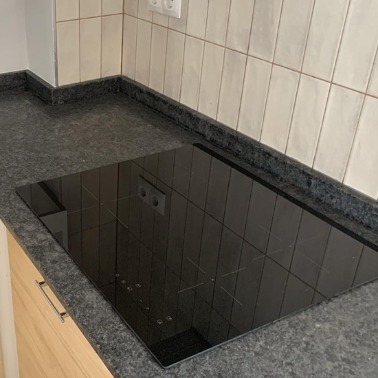 Placa de inducción negra empotrada en encimera de Granito Steel Gray