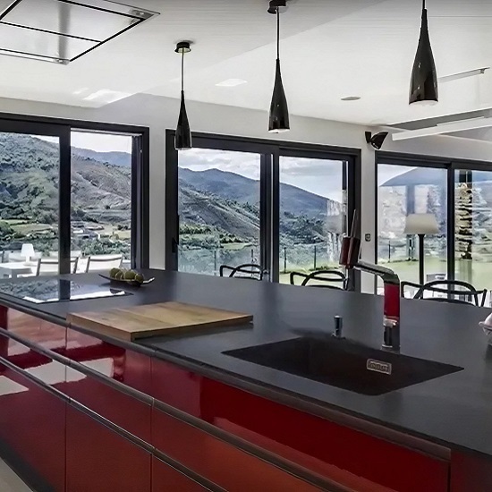 Canto recto en encimera porcelánica negra con muebles rojos y vistas a la montaña