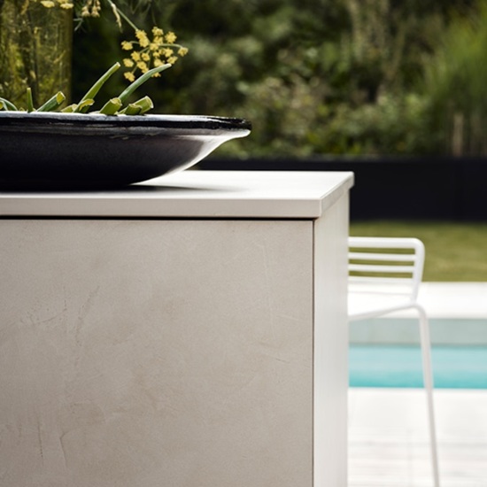 Canto recto en encimera exterior Dekton beige con bol negro y jardín al fondo