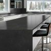 Isla de cocina en porcelánico Techlam Pierre Bleue negro con taburetes y muebles blancos