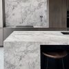 Detalle encimera cuarcita Terra Oriella / Superwhite en isla de cocina con taburete