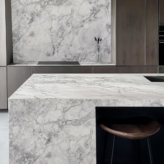 Detalle encimera cuarcita Terra Oriella / Superwhite en isla de cocina con taburete