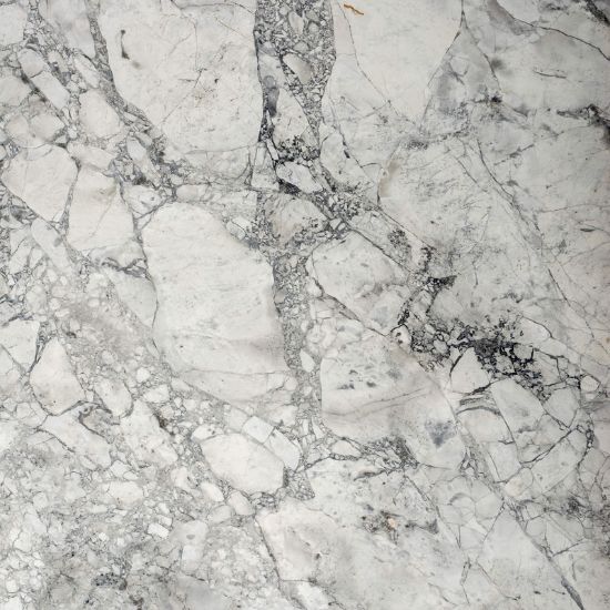 Cuarcita Terra Oriella / Superwhite detalle textura blanca con vetas negras y grises fragmentadas